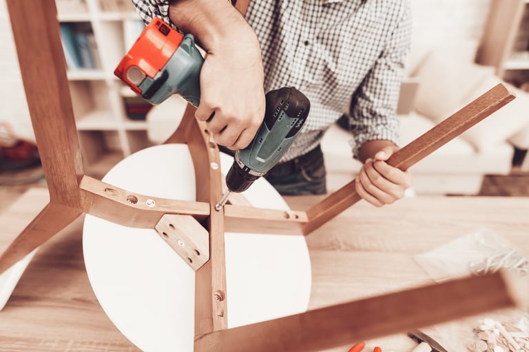 Assemble Furniture. Man Repairing Chair. Man Collects Chair. Furniture Assembler with Drill. Bright Interior. Craftsman with Tools Repairs Chair.