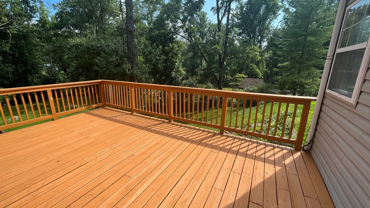 Beautiful wooden deck with sliding glass doors providing unobstructed view of lush green landscape, perfect outdoor living space