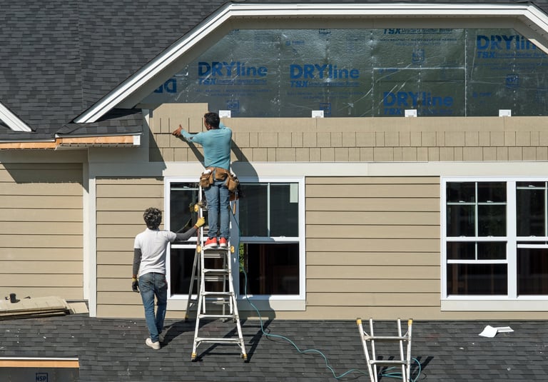 Dayton, Ohio - August 21, 2024: Construction workers install shake siding on second story Gambrel roofline as part of new condo housing development.