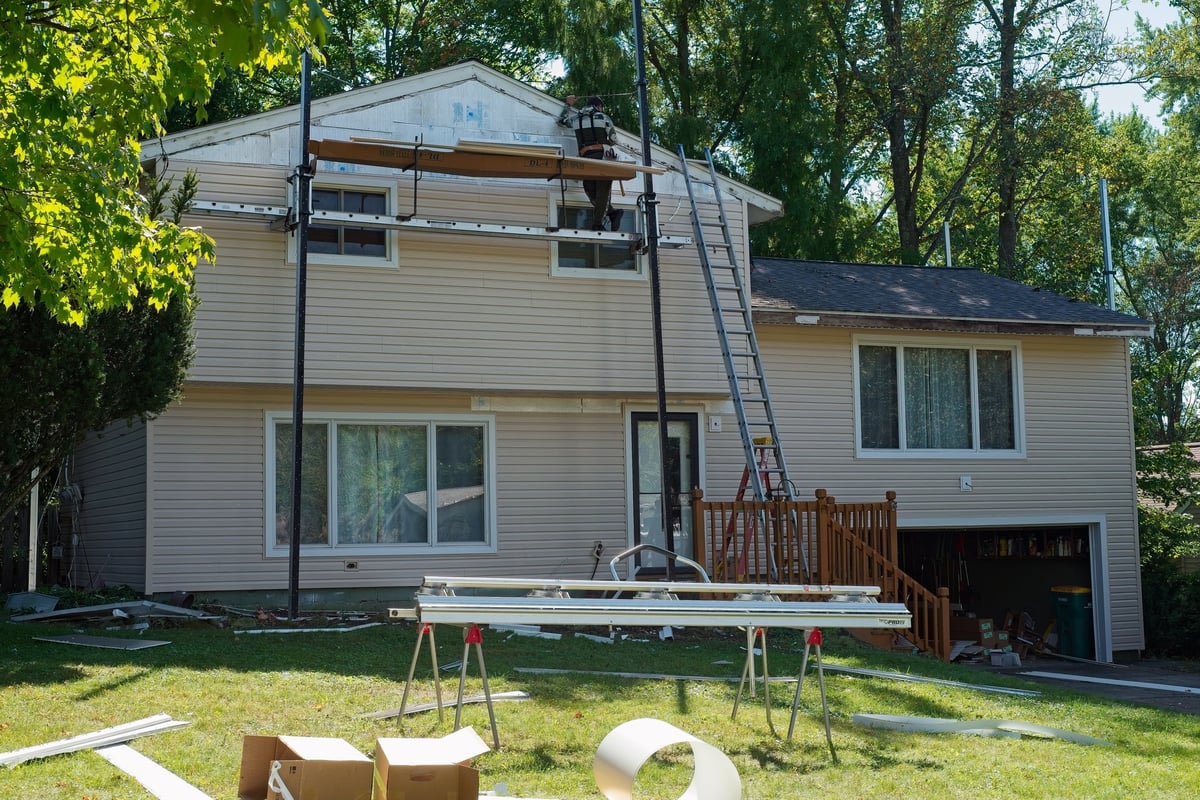 Home siding replacement project with new vinyl siding installed on split-level suburban house, professional transformation
