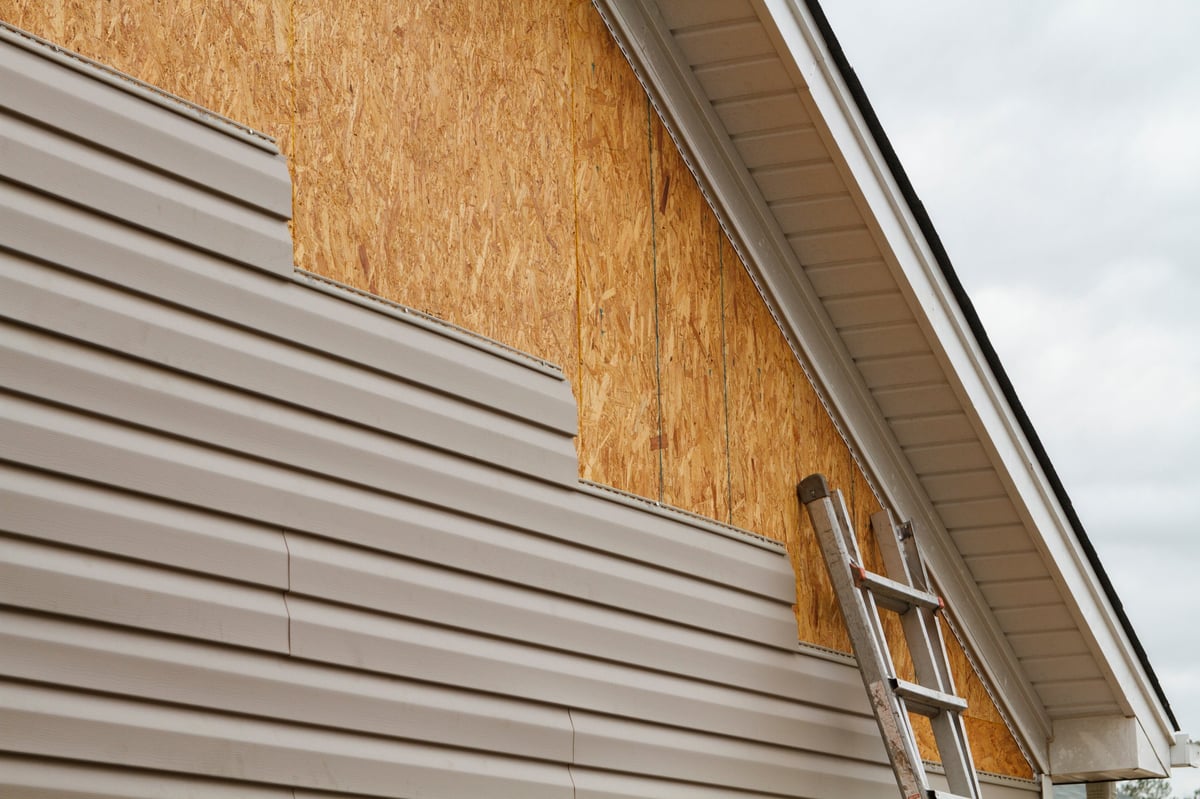 Beautiful new beige vinyl siding installed over OSB substrate on residential home, complete exterior transformation