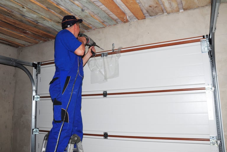 Contractor installing garage door and drilling hole for garage door opener